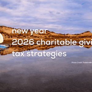 Sand dunes under a blue sky with text: new year 2026 charitable giving tax strategies. A small logo and photo credit appear in the corners.